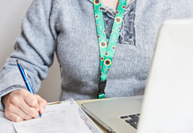 Woman with laptop and notepad wearing sunflower lanyard