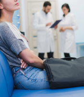 Woman waiting for hospital appointment with doctors in background