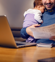 Man holding baby and looking at work documents