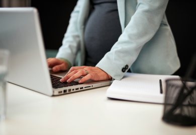 Pregnant employee typing at desk