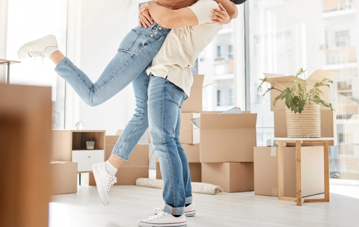 Man holding woman up in air, surrounded by carboard boxes