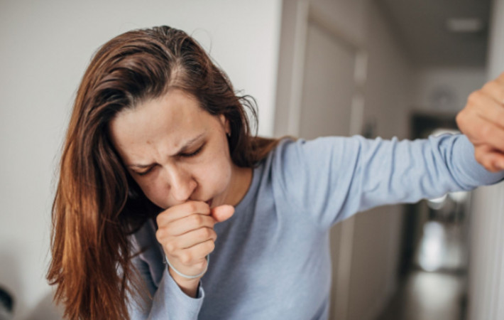 woman coughing into her fist