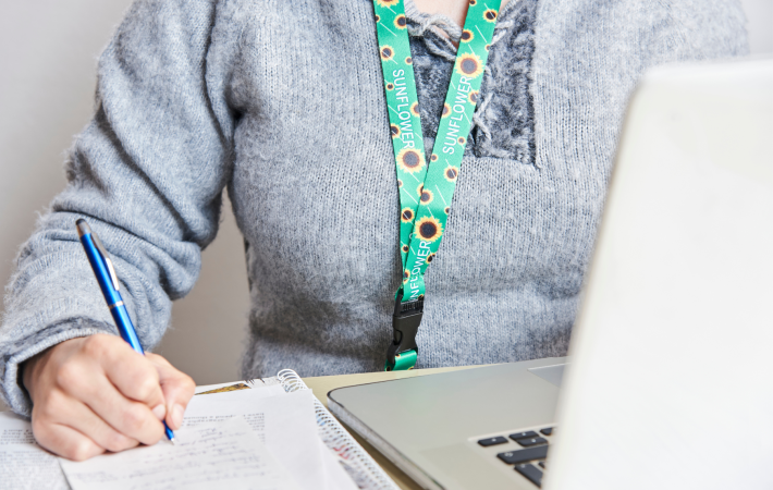 Woman with laptop and notepad wearing sunflower lanyard
