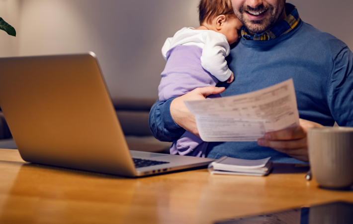 Man holding baby and looking at work documents