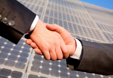 Shaking hands in front of solar panels