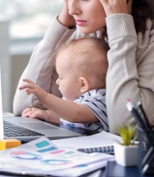 Stressed woman trying to work at laptop with baby on lap